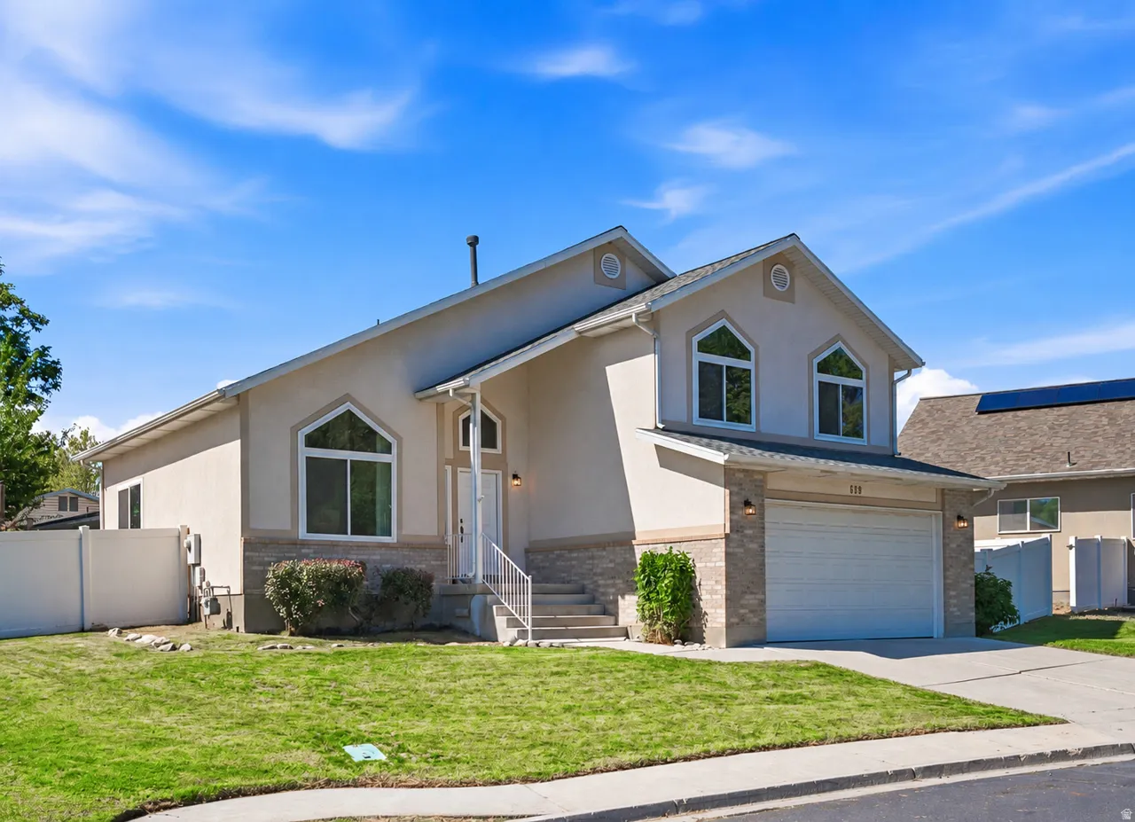 Stucco exterior with stone accent detailing, arched windows, covered entryway, and an attached two-car garage