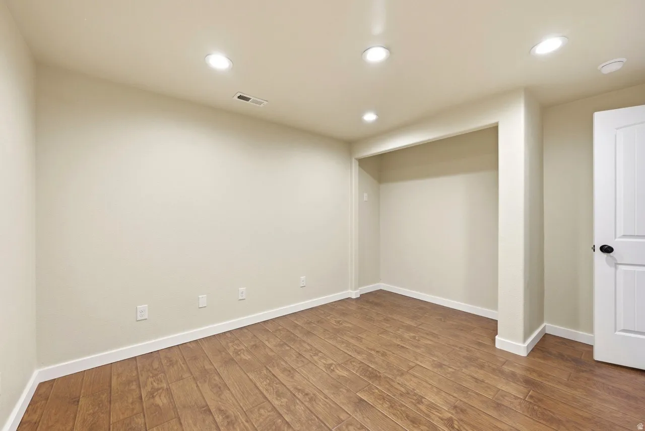 Wood-finish flooring with white trim, recessed lighting, and a built-in alcove