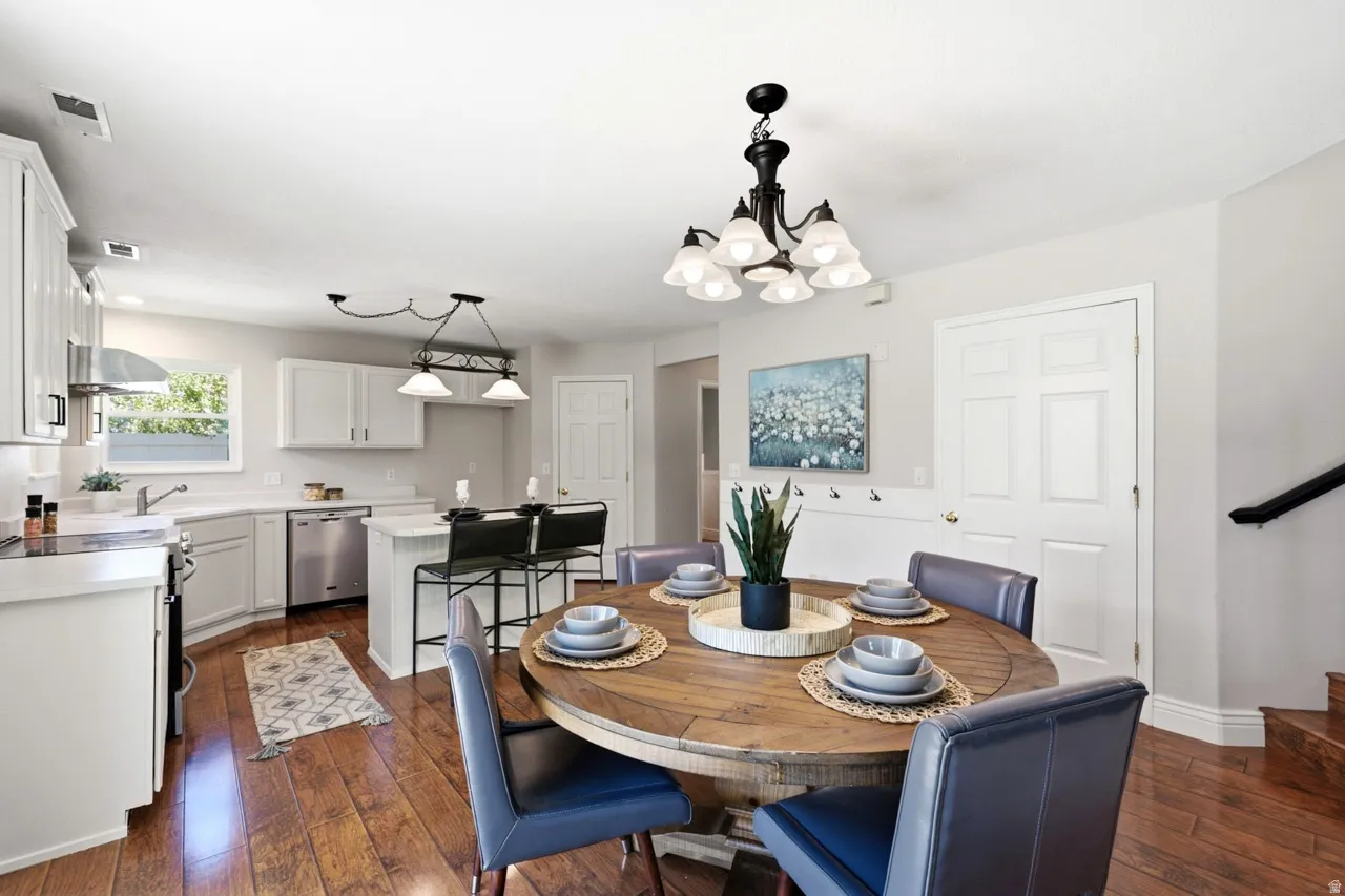 Kitchen featuring white cabinetry, stainless steel appliances, a center island with seating, and wood-finish flooring