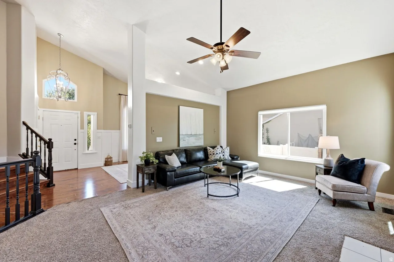 Vaulted ceilings, wood-finish flooring, wainscoting detail, and a ceiling fan with integrated lighting
