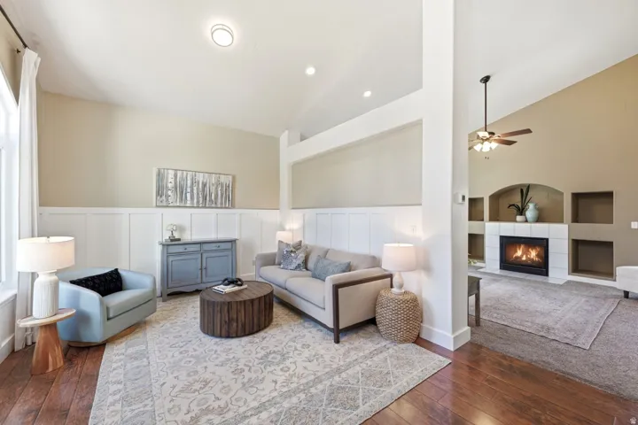 Vaulted ceilings, wood-finish flooring, white wainscoting, recessed lighting, and a tiled fireplace surround with built-in shelving