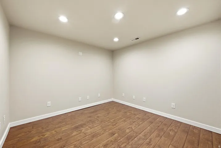 Wood-finish flooring with white trim, recessed lighting, and neutral wall tones