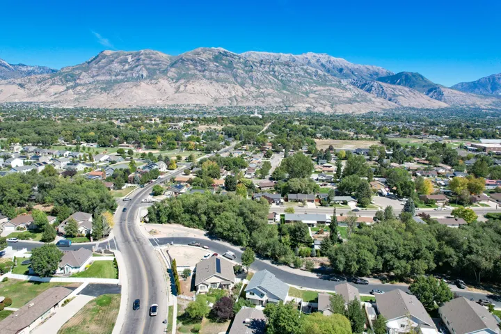 Expansive residential area featuring established homes, mature trees, a clear road network, and a prominent mountain backdrop