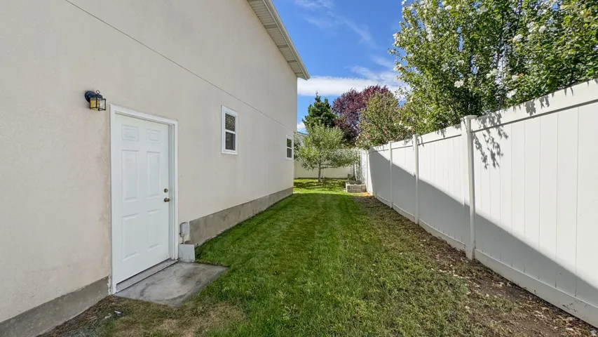 Exterior stucco siding with a white pedestrian door and black wall-mounted lighting