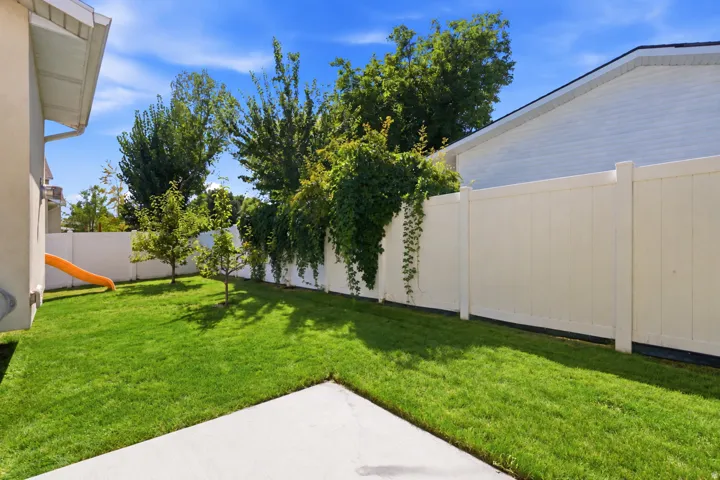 Expansive backyard featuring a well-maintained lawn, mature trees, and a privacy fence