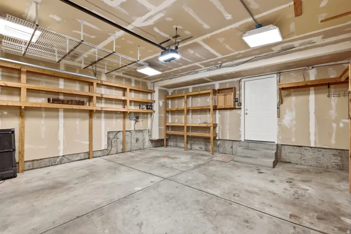 Concrete flooring with a built-in shelving system, overhead storage racks, and task lighting