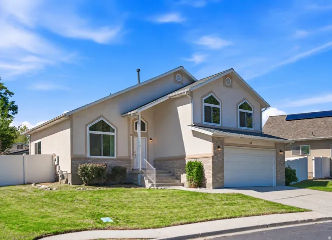 Stucco exterior with stone accent detailing, arched windows, covered entryway, and an attached two-car garage