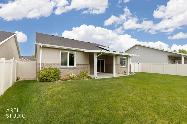 Expansive grass lawn with a covered patio, vinyl fencing, and a pergola