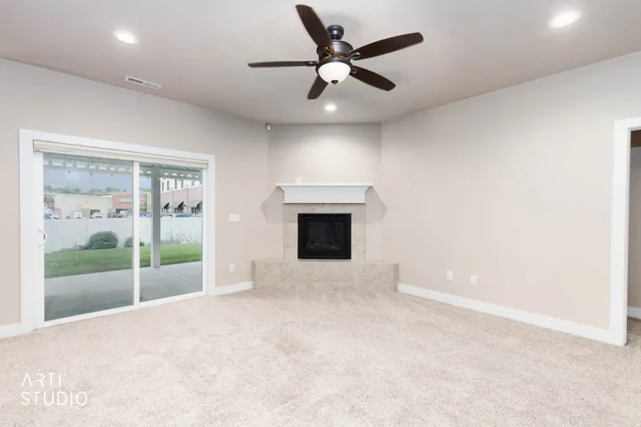 Recessed lighting, ceiling fan, fireplace with mantel, and sliding glass door to outdoor patio
