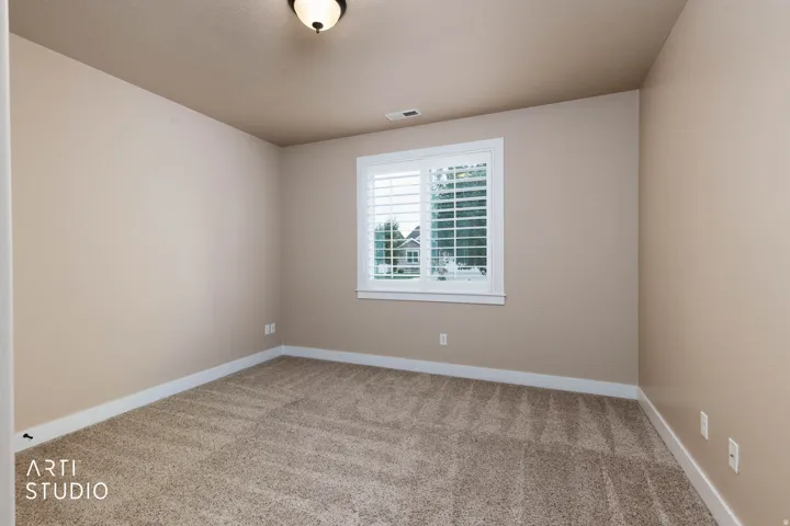 Window with plantation shutters, overhead light fixture, light-colored walls, and neutral carpeting