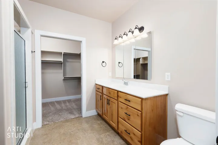 Wood-finish vanity with white countertop, integrated sink, and dark hardware
