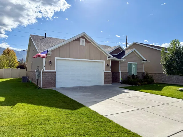 Residential exterior featuring a two-car garage, partial brick facade, and a concrete driveway
