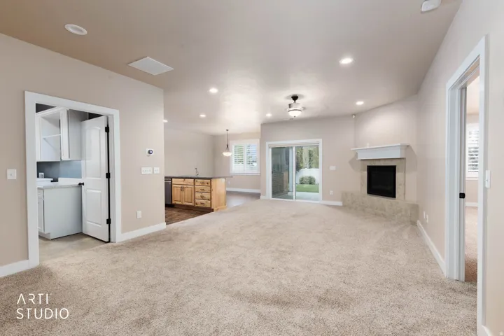 Recessed lighting, sliding glass door, built-in fireplace, wood-finish kitchen island, and white shaker cabinetry