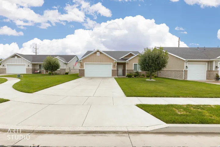 Contemporary residence with an attached garage, featuring a gravel and stucco exterior, a paved driveway, and a manicured lawn