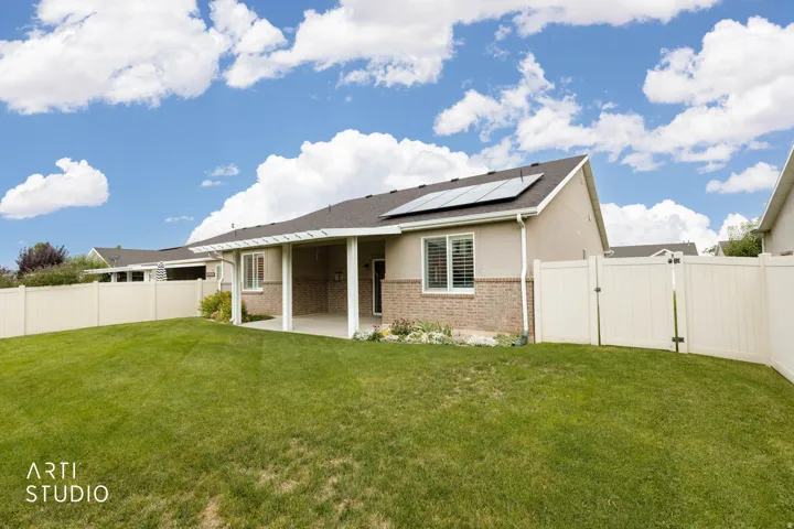 Expansive backyard with a covered patio, solar panels, and full perimeter fencing