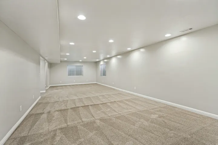 Spacious room with recessed lighting, light neutral wall color, and patterned carpet flooring