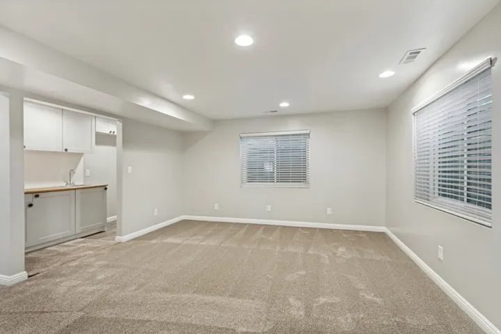 Recessed lighting, wood-finish countertop, light gray cabinetry, built-in sink, and light neutral carpeting
