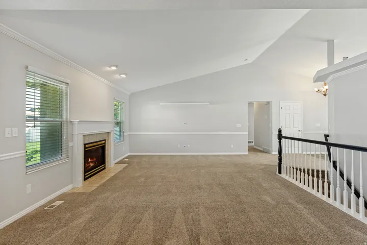 Vaulted ceiling, fireplace with hearth, and carpeted flooring