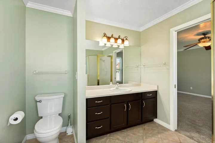 Vanity with a single basin sink, integrated countertop, and rich wood cabinetry
