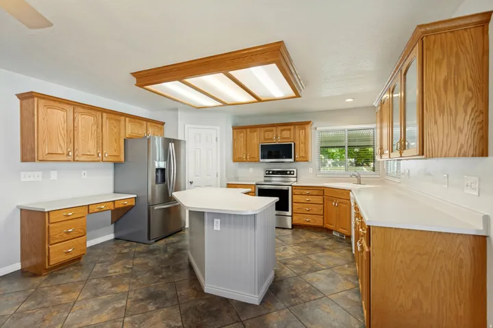 Kitchen with ample wood cabinetry, a central island, and white solid surface countertops