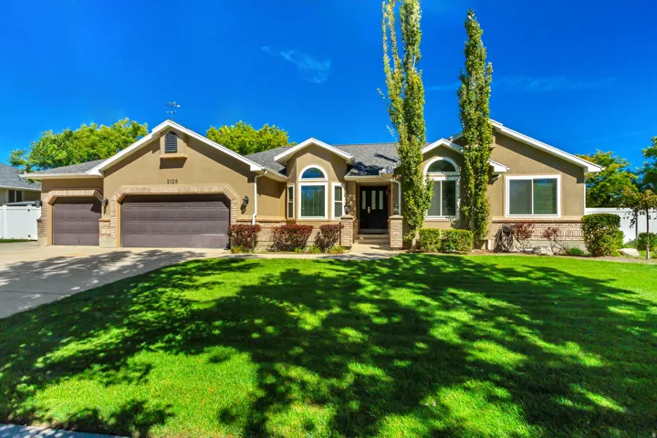 Stucco exterior with stone accenting, arched windows, covered entry, and attached multi-car garage