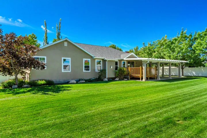 Expansive rear yard with a wood deck, stucco exterior, and attached pergola