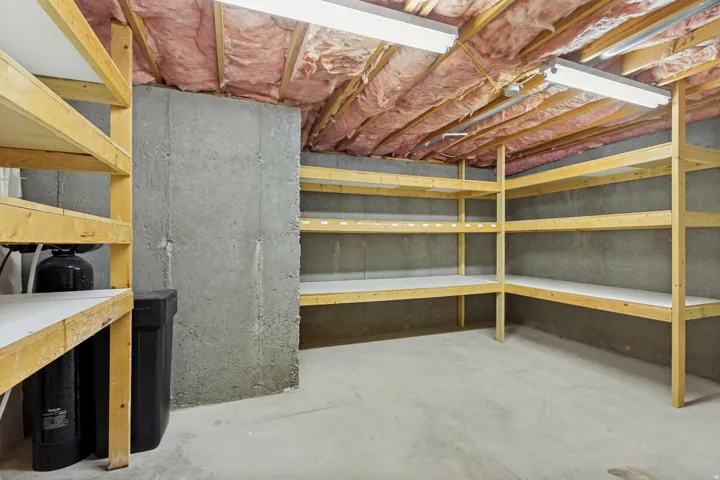 Expansive storage area featuring built-in shelving, concrete walls, and overhead fluorescent lighting