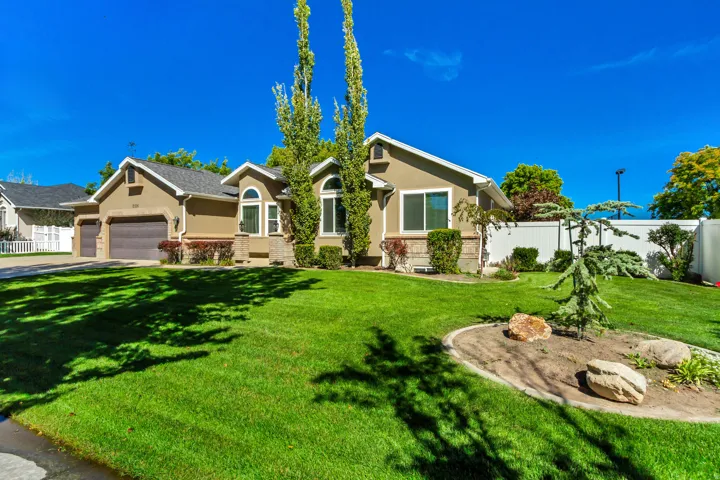 Stucco exterior with stone accents, arched windows, attached two-car garage, and a manicured lawn