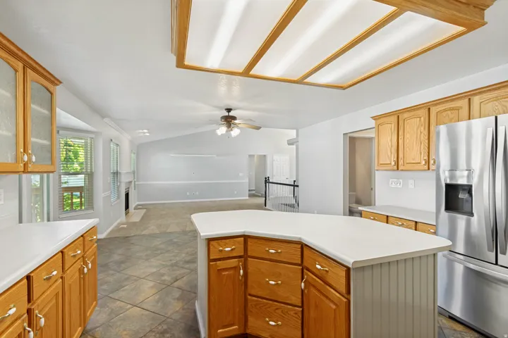 Kitchen featuring a center island, wood-finish cabinetry, stainless steel refrigerator, white countertops, and tile flooring