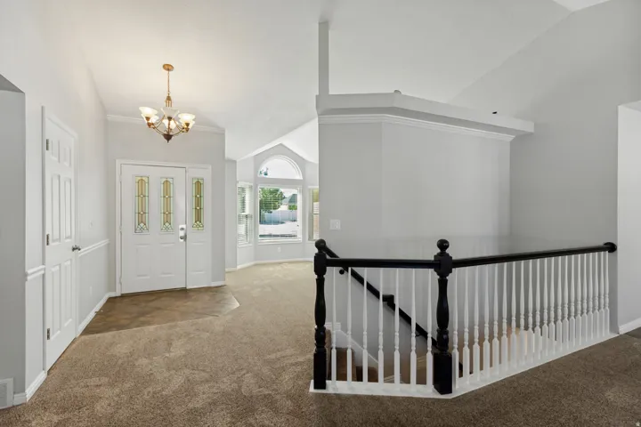 Foyer with vaulted ceilings, decorative double entry doors, an arched window, and a chandelier