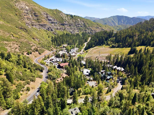 Mountain valley location featuring a winding road, dense evergreen forests, and varied terrain