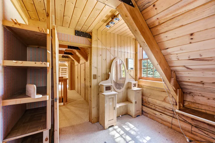 Exposed wood ceiling, wood-paneled walls, built-in shelving, natural wood window frame, and sloped wood ceiling