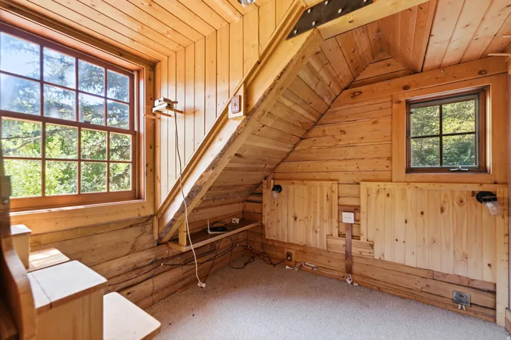 Pine wood paneling throughout, multiple windows, and a carpeted floor