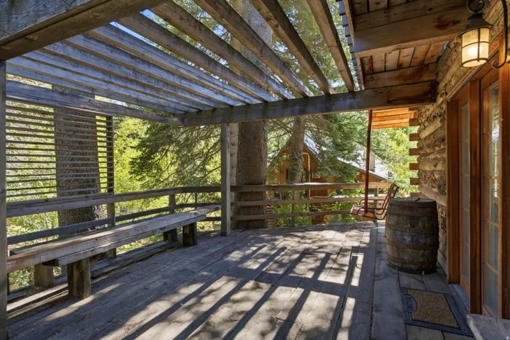 Expansive wood deck with a slatted pergola, integrated wood bench seating, and wood railing