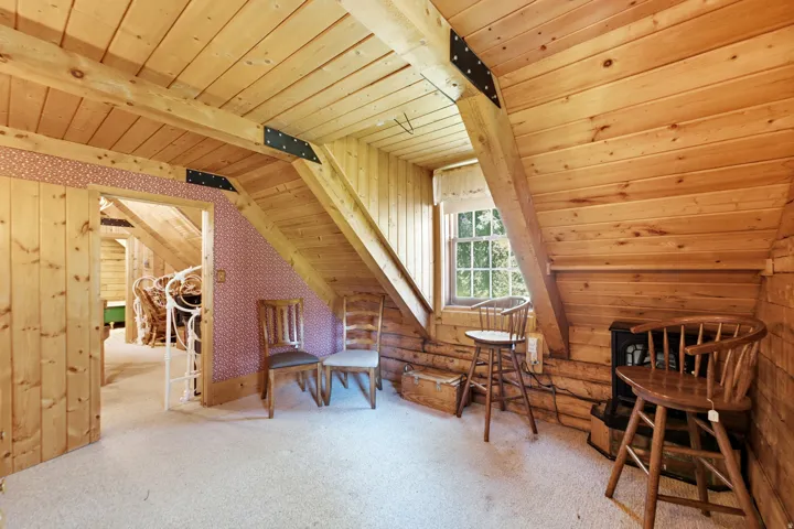 Exposed wood beams, vaulted wood-finish ceiling, wood-paneled walls, and a casement window