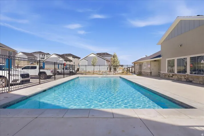 Community swimming pool with surrounding concrete decking and a full perimeter fence