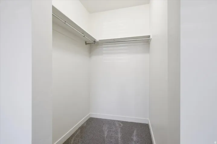 Recessed closet with a single hanging rod, upper shelf, and neutral carpeting