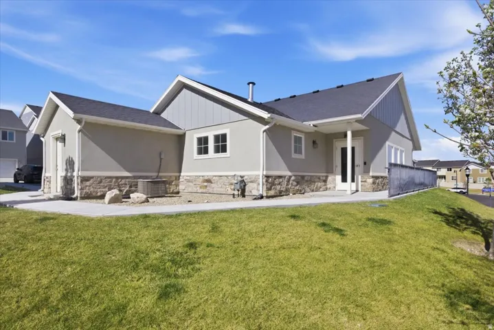 Contemporary exterior with a dark shingle roof, light stucco siding, stone veneer accents, and white-framed windows