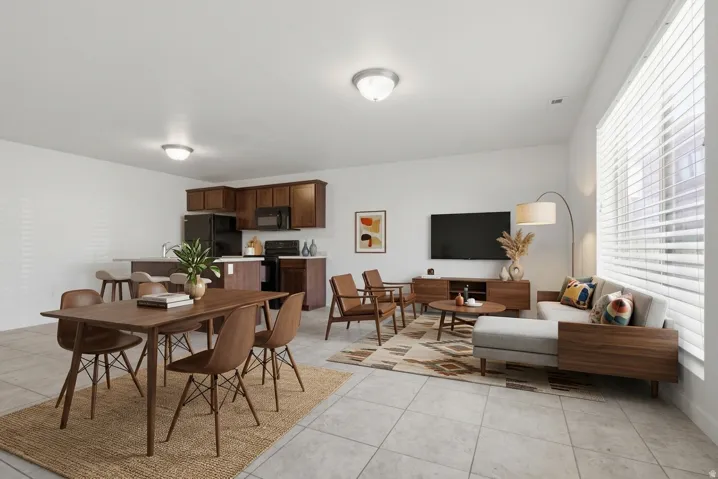 Open-concept living space featuring light tile flooring, dark wood-finish cabinetry, a kitchen island with a breakfast bar, and recessed lighting