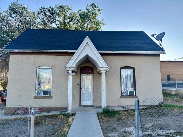 Stucco exterior with a dark shingle roof and a covered entryway