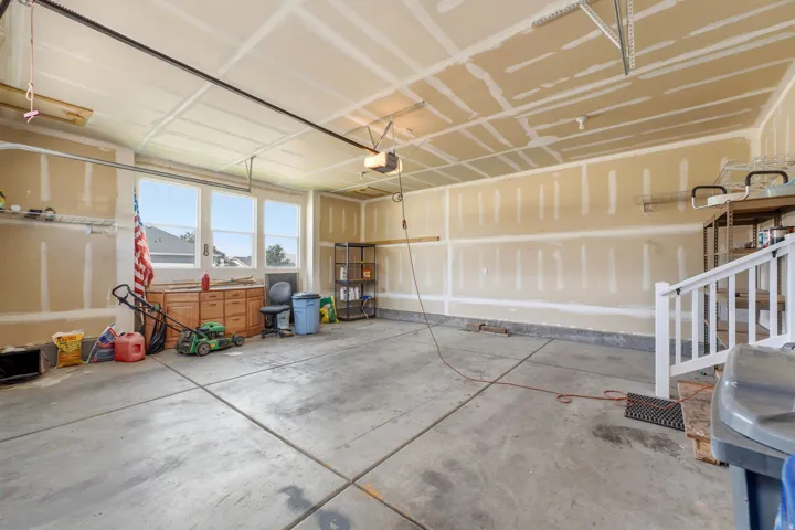 Concrete flooring, multiple windows, built-in shelving, white railing, and an overhead garage door mechanism