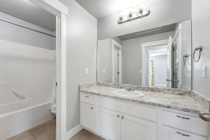 Bathroom vanity with a white cabinet, integrated sink, and stone-finish countertop