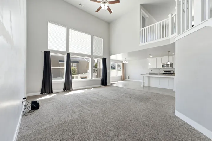 Two-story living area with high ceilings, large windows, and a ceiling fan