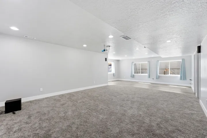 Spacious room with gray carpet flooring and recessed lighting