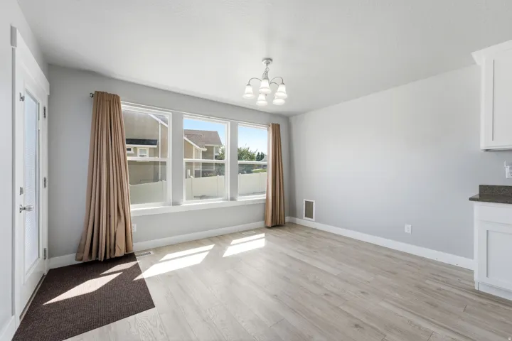 Light wood-finish flooring, white trim, and a white ceiling-mounted chandelier