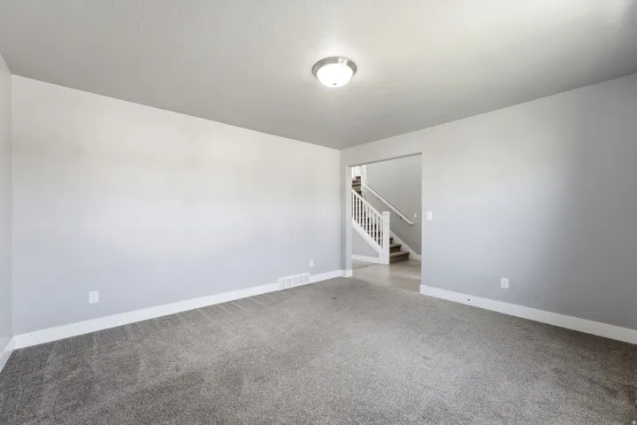 Neutral gray wall finishes, gray carpeting, and a flush mount ceiling light fixture