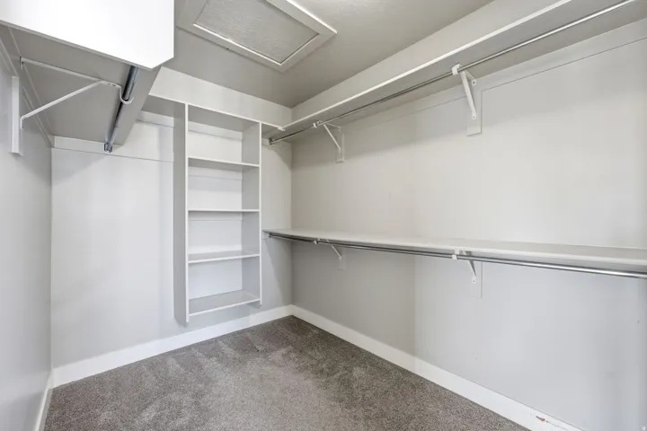 Built-in shelving, chrome hanging rods, and gray-toned carpeting