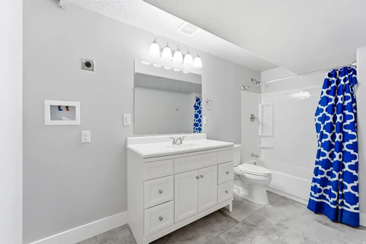 White vanity with an integrated sink, large wall-mounted mirror, and overhead light fixture