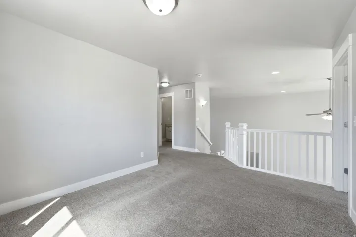 Carpeted flooring, white interior walls, white railings, and flush mount lighting