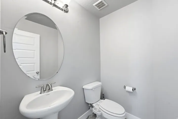 Pedestal sink with chrome-finish faucet, elongated toilet, and oval wall mirror